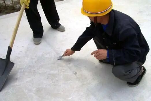 Worker scraping and leveling the substrate before installing an SBS waterproofing membrane